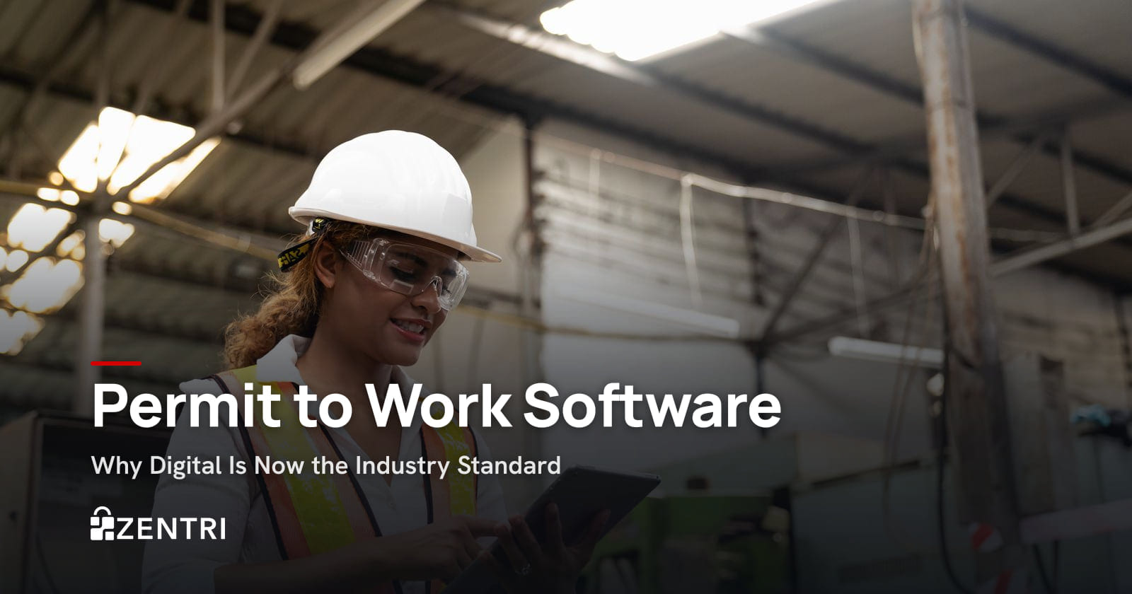 Factory worker in a hard hat and safety glasses using a tablet
